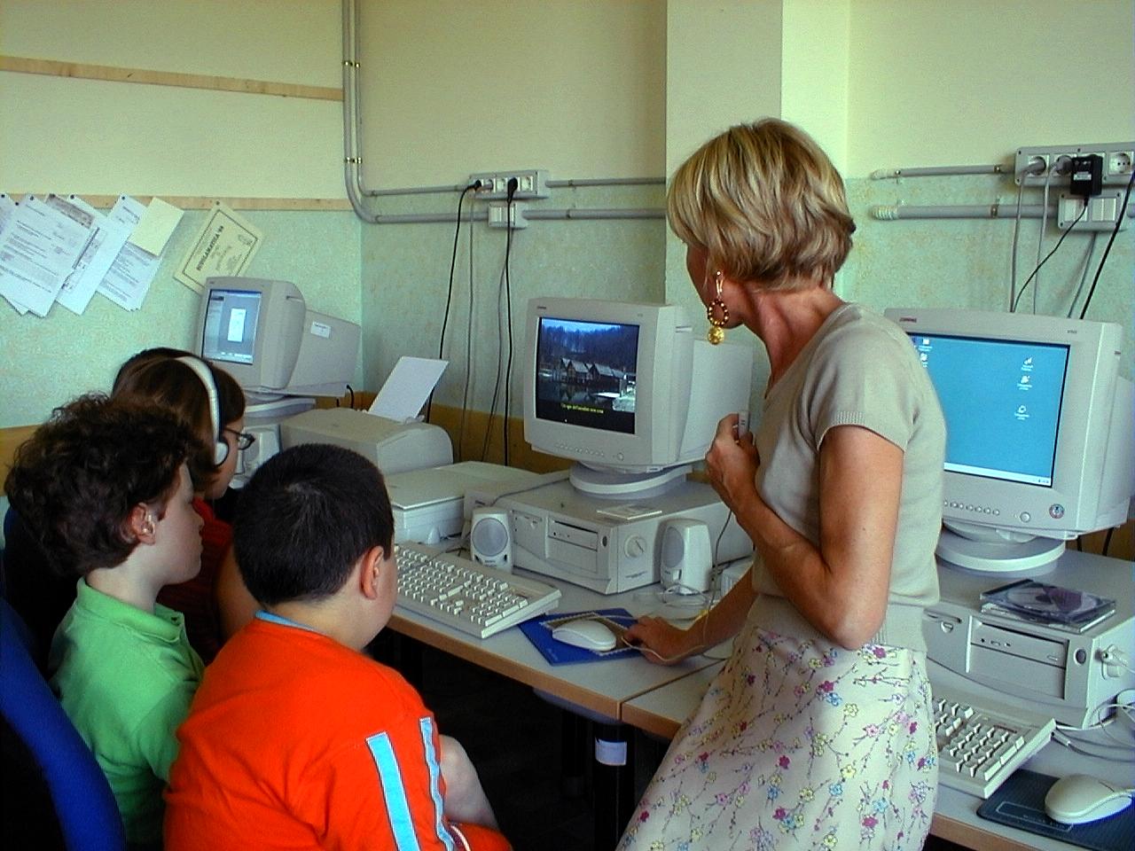 foto di un'insegnante con 3 alunni davanti a dei PC