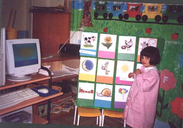 foto di un'alunna in classe accanto ad un computer ed una lavagna